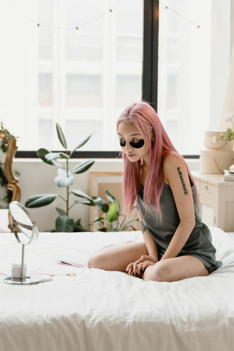 A young woman enjoying a self-care skincare routine with eye patches in a cozy indoor setting.